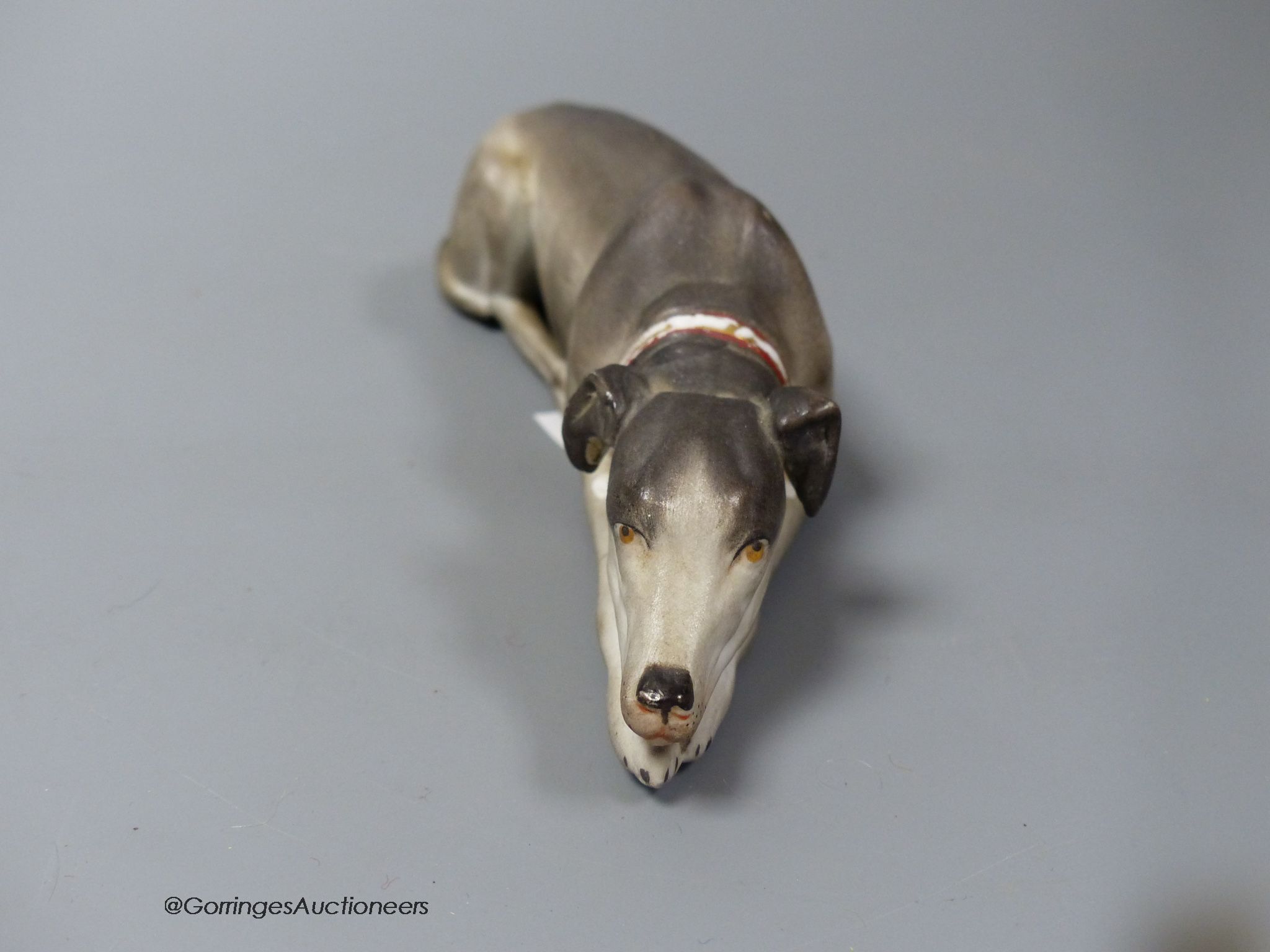 A Continental bisque reclining dog, 17cm